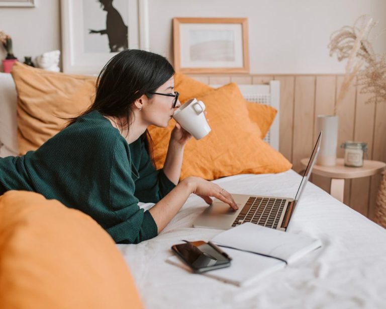e-learning-luno Femme couchée sur son lit buvant une tasse thé et suivant un cours d'e-learning de Luno Académie sur son ordinateur