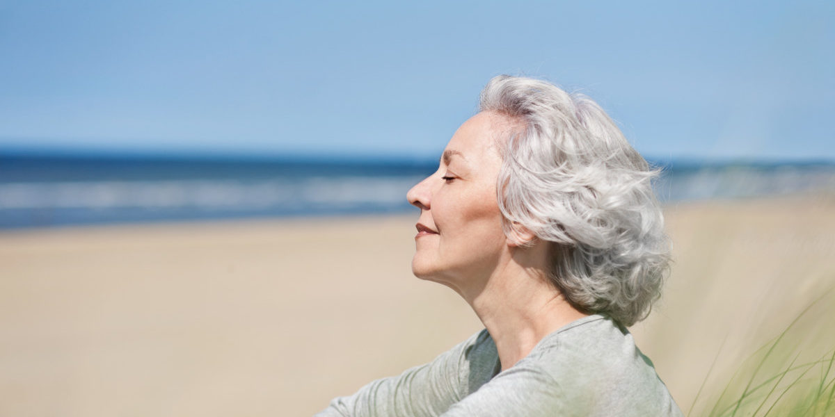 attraktive, grauhaarige Frau genießt das Meer Le soleil et le vieillissement prématuré de la peau
