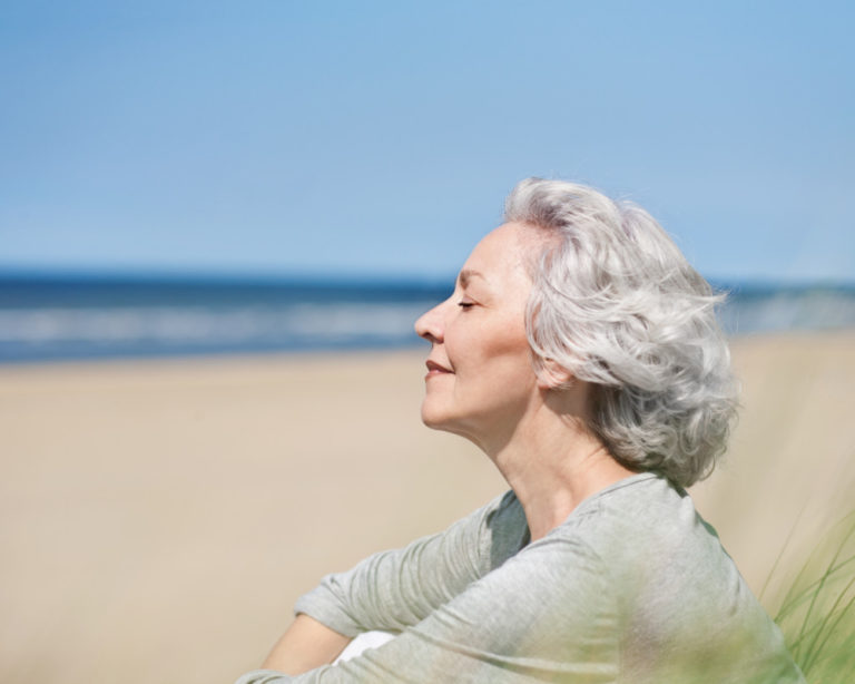 attraktive, grauhaarige Frau genießt das Meer Le soleil et le vieillissement prématuré de la peau
